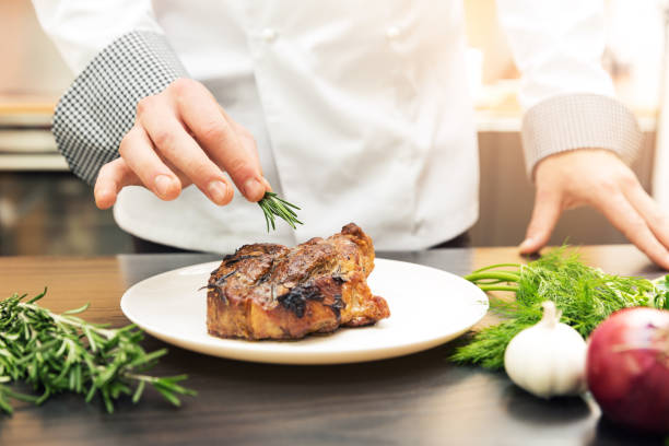 istock chef decorating roasted meat with herbs 640942038