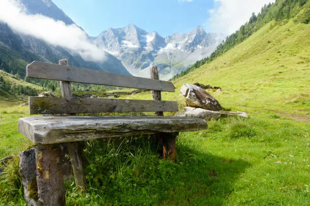 Wooden rest bench with mountains in the background in Tyrol
