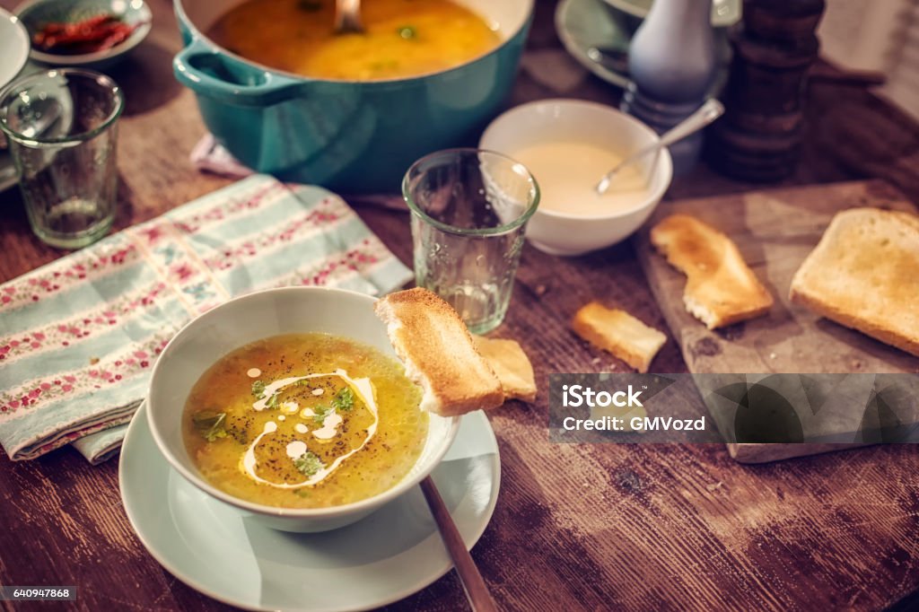Eating Delicous Chicken Soup with Carrots and Parsnips Little girl eating delicious chicken soup with carrots, onions and parsnips. The soup is served in a bowl with creme fresh and grilled toast. Appetizer Stock Photo