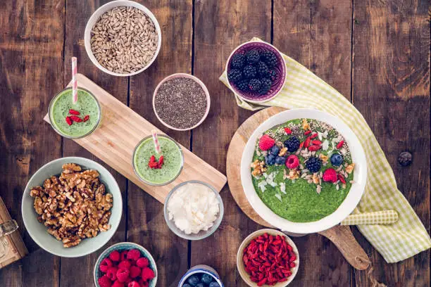 Eating healthy superfood dishes like green chia smoothie with berries in a bowl, yoghurt with mango and nuts, short grained rice with yoghurt, honey, chia seeds.