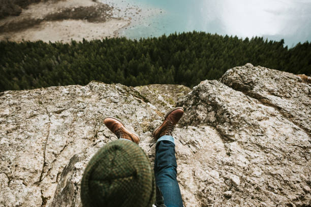 A young adult man enjoys some quiet time in nature, taking in the scenic views of a mountain hike.  Shot at Rattlesnake Ridge / Ledge in Snoqualmie, Washington, USA.