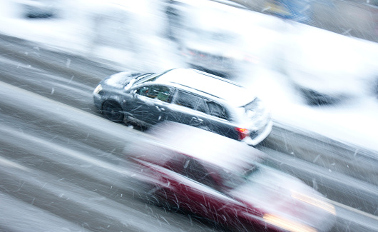 Belgrade, Serbia - January 9, 2017: Driving cars in the street hit by the heavy snowfall, in motion blur, high angle view