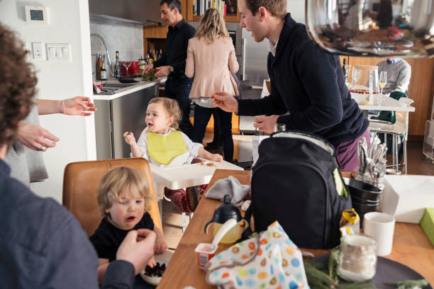 Fathers feeding toddlers before big family dinner, lots of action. stock photo