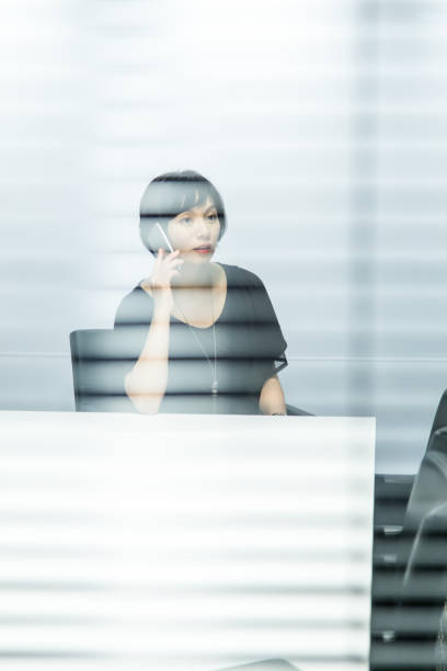 istock Looking Through Window Blinds at Woman on Telephone 640959846