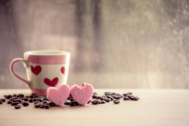 heart pink cookies and coffee cup on rainy day window background in vintage color tone