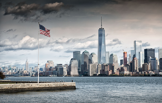 Grey cloud hangs above American Flag overlooking the New York City financial district
