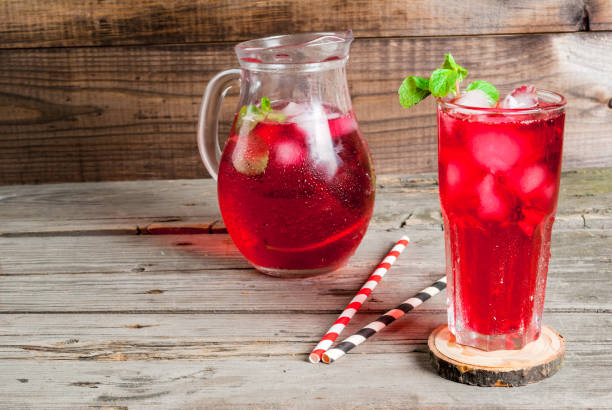 Summer iced drink - tea or juice Summer iced drink - tea or juice with ice and mint. On rustic wooden table, copy space strawberry crush stock pictures, royalty-free photos & images
