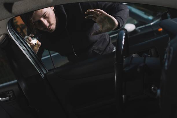 авто вор ищет интерьер автомобиля - car stealing thief car thief стоковые фото и изображения