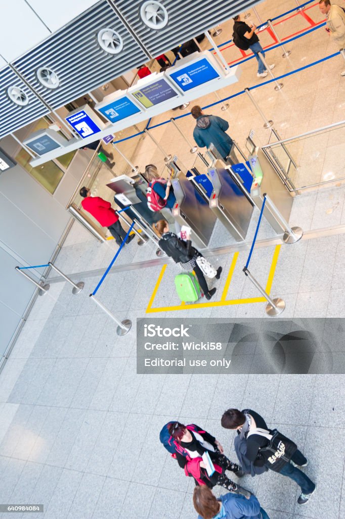 Air passengers entering a automated boarding ticket control Air travelers at the International Airport Frankfurt, Germany entering the automated boarding ticket control, the automated boarding ticket control is supervised by a security staff (red jacket). The Ticket control is located at the front of the passport control. Airline Check-In Attendant Stock Photo