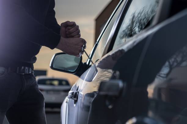Auto thief in black balaclava trying to break into car Auto thief in black balaclava trying to break into car with screwdriver. Car thief, car theft burglary photos stock pictures, royalty-free photos & images