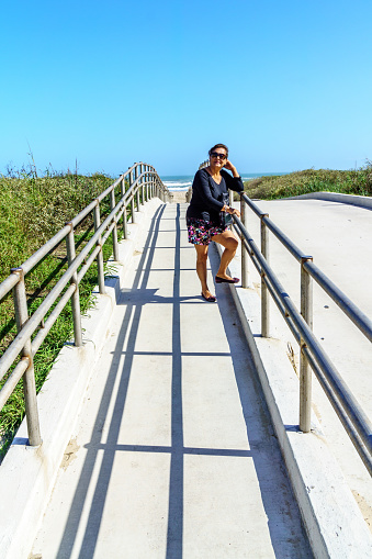 Attractive senior woman walking along boardwalk on the beach