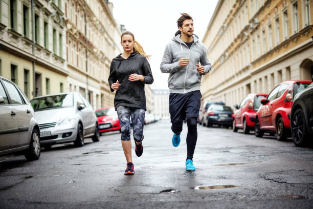 couple running together in the city - running jogging urban scene city life imagens e fotografias de stock