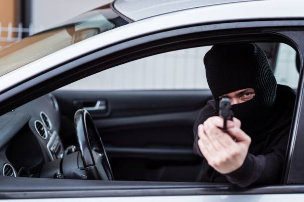 istock Man in black balaclava with handgun driving a car. 640989368