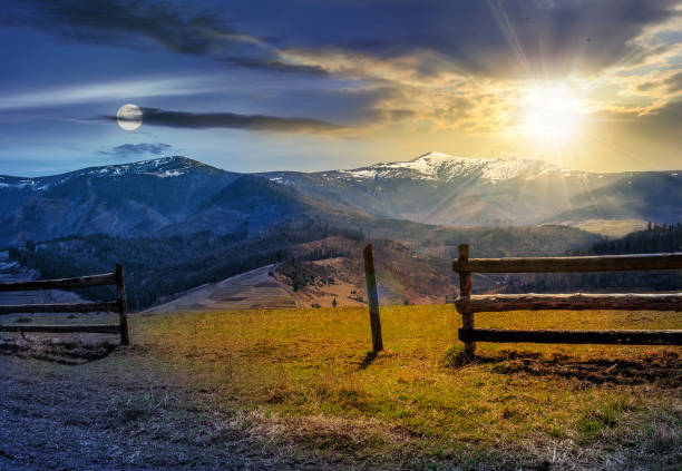 istock time change concept. fence on rural field in spring 640998156