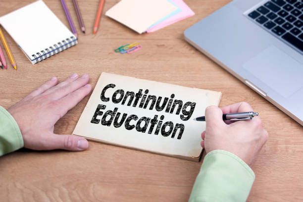 istock Hand writing Continuing Education. Office desk with a laptop and stationery 640999698