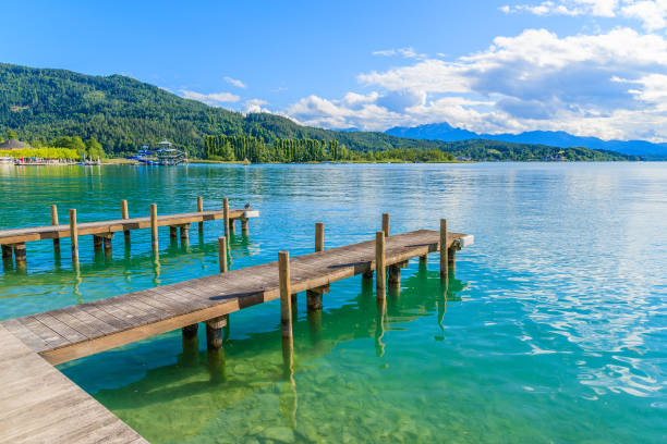 Wooden pier for mooring boats on Worthersee lake on beautiful summer day, Austria Most popular lake in Austria for summer holidays alpine climate photos stock pictures, royalty-free photos & images