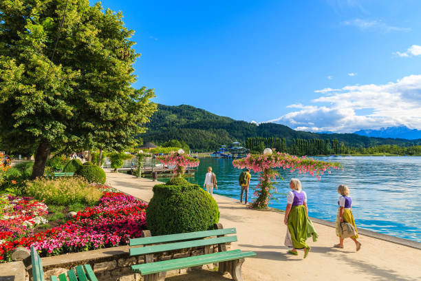 WORTHERSEE LAKE, AUSTRIA WORTHERSEE LAKE, AUSTRIA - JUN 20, 2015: two women wearing traditional clothes walking along Worthersee lake shore during summer pörtschach am wörthersee stock pictures, royalty-free photos & images