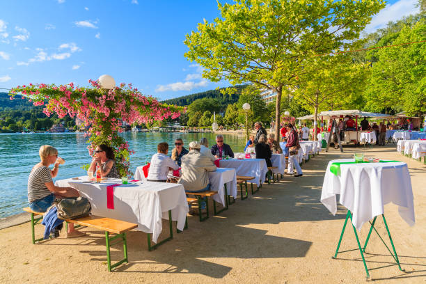 WORTHERSEE LAKE, AUSTRIA WORTHERSEE LAKE, AUSTRIA - JUN 20, 2015: people sitting at tables along Worthersee lake shore during summer beer festival. pörtschach am wörthersee stock pictures, royalty-free photos & images