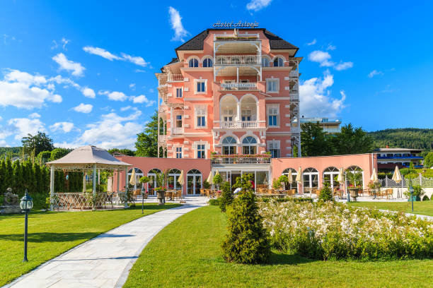 WORTHERSEE LAKE, AUSTRIA WORTHERSEE LAKE, AUSTRIA - JUN 20, 2015: luxury hotel Astoria and its gardens on shore of beautiful alpine lake Worthersee pörtschach am wörthersee stock pictures, royalty-free photos & images