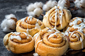 close up cinnamon rolls in a plate, on a dark background with cement cotton boxes behind.