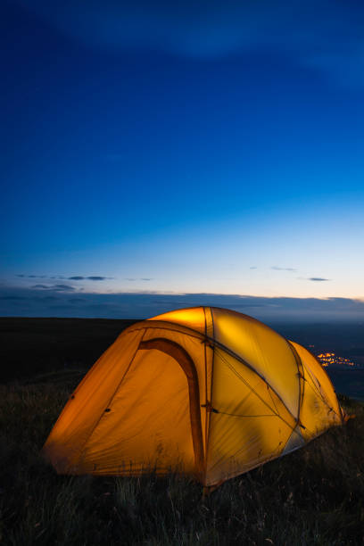 istock Orange dome tent warmly illuminated on mountain ridge at dusk 641003718
