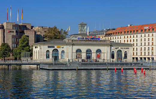 Geneva, Switzerland - 24 September, 2016: people at the La Cite du Temps building, view from the Pont des Bergues bridge. La Cite du Temps is a public exhibition center focusing on the world of time, hosting a wide variety of different exhibitions and activities, including a permanent exhibition of Swatch watches.