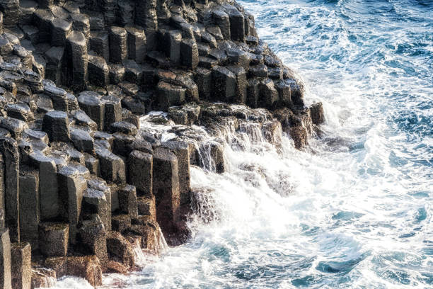 waves hitting the side of daepo jusangjeolli cliff stone pillars in jejudo, south korea