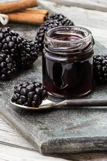 Homemade blackberry jam. Blackberries, cinnamon stick and rustic spoon on the cutting board