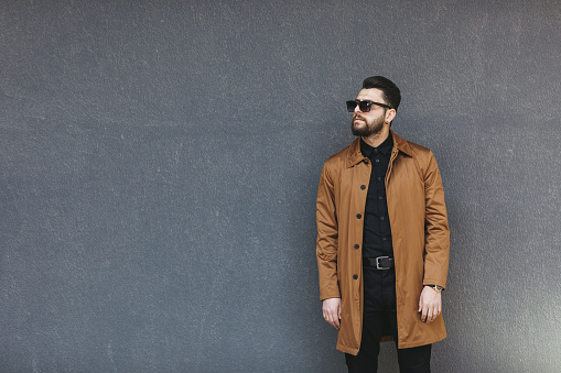 Young man posing on gray wall.