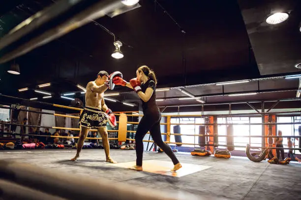 Modern gym facility in Bangkok, young athletes training for a Muay Thai class, women and men