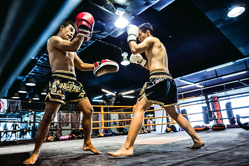 Muay Thai match on boxing ring in Thailand inside a gym facility.