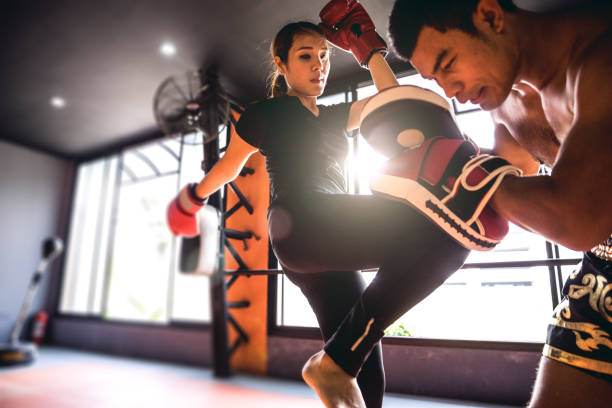 Muay Thai workout - Motivational training at the gym facility Modern gym facility in Bangkok, young athletes training for a Muay Thai class, women and men women boxing sport exercising stock pictures, royalty-free photos & images