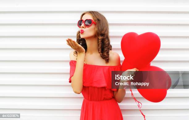 Portrait Woman In Red Dress Sends Air Kiss With Balloon Heart Shape Over White Background Stock Photo - Download Image Now