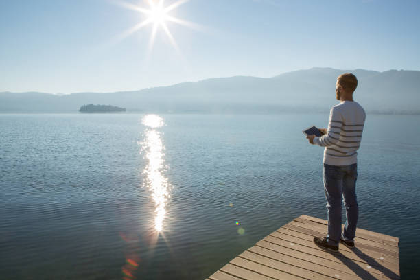 istock Young man relaxing on lake pier with digital tablet 641036426