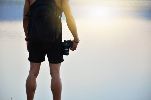 istock man stand beside lake and holding camera 641037114