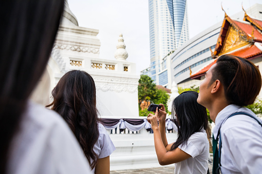 Thai students in uniform in Bangkok take a break together before going to University - Thailand.
