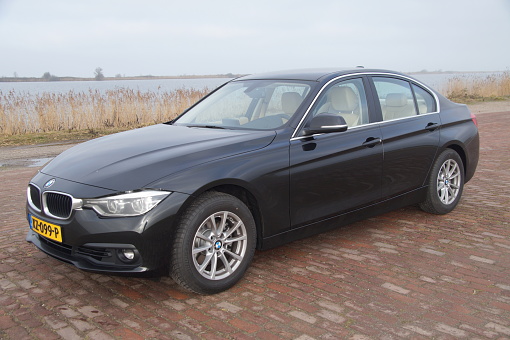 Almere, Flevoland, The Netherlands - Februari 5, 2017: Black BMW 320I parked by the side of the road in the city of Almere. Nobody in the vehicle.