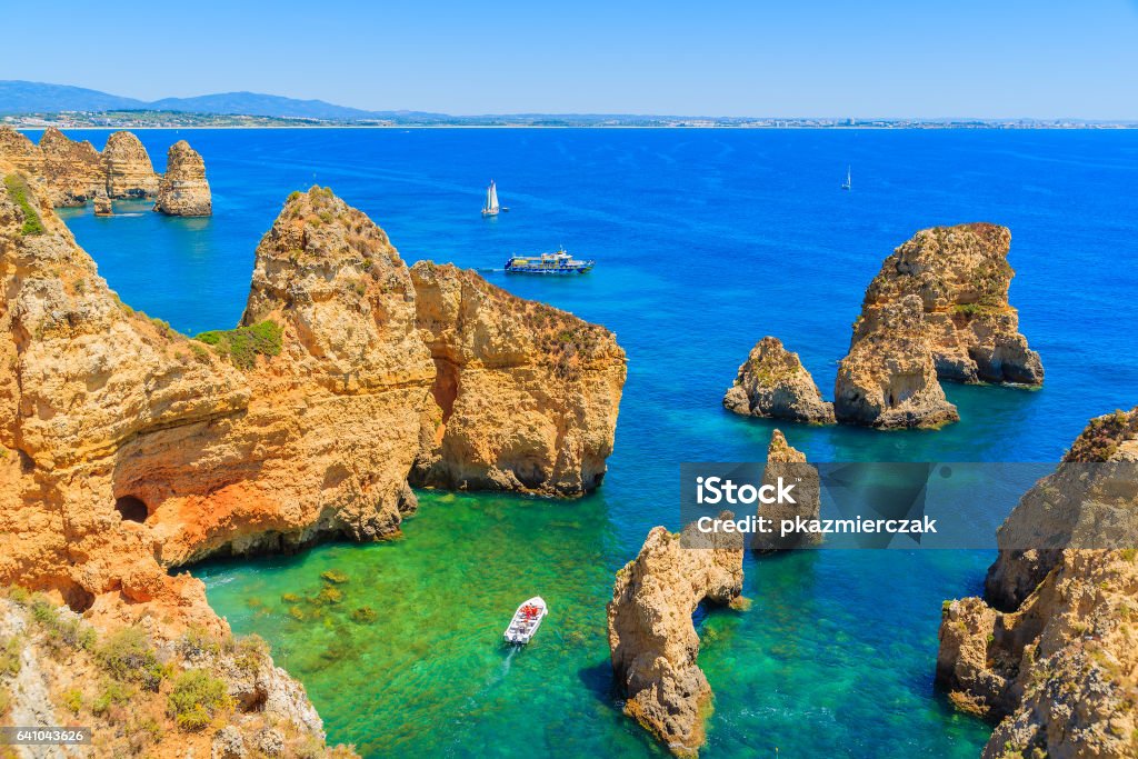 Fishing boat on turquoise sea water at Ponta da Piedade, Algarve region, Portugal Algarve region in south of Portugal is very popular tourist destination Algarve Stock Photo