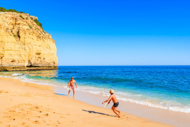 vale centianes beach, portugalia - 16 maja 2015: chłopiec bawi się z ojcem na piaszczystej plaży w regionie algarve, portugalia. - men footprint beach sunset zdjęcia i obrazy z banku zdjęć