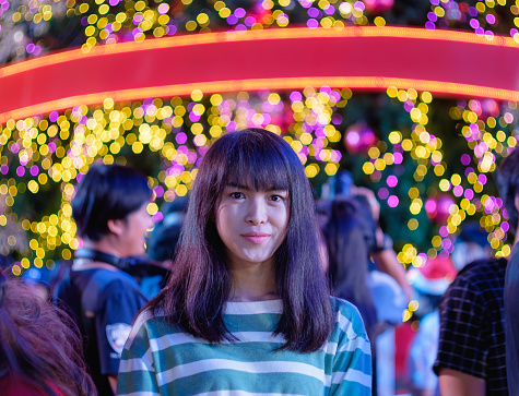 young adult long hair cute asian girl at Central World with colorful bokeh light on background, Christmas day event in Bangkok, Thailand