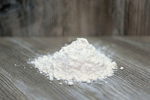 Heap of white flour. Isolated on wooden background.