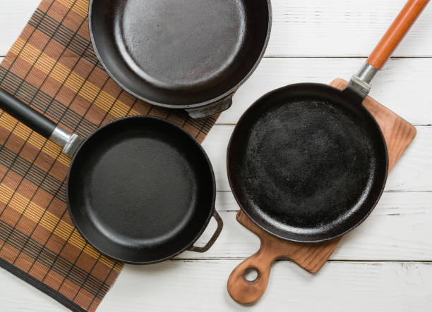 istock Several empty cast-iron frying pans on a white wooden background. View from above 641059686