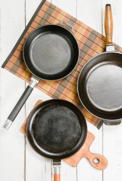 istock Several empty cast-iron frying pans on a white wooden background. View from above 641059756