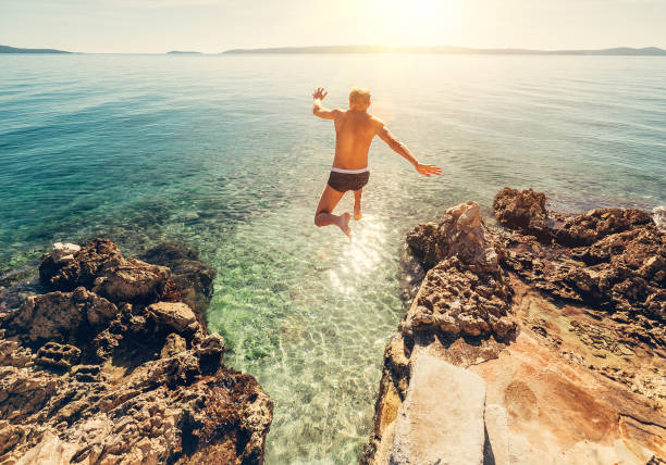 Man jumps in blue sea lagune water Man jumps in blue sea lagoon water jumping into water stock pictures, royalty-free photos & images