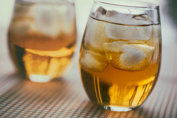 Two glasses of the French aperitif Pineau des Charentes, also called Pineau Charentais or Pineau. It is a fortified wine (mistelle) since Cognac eau-de-vie has been added to it. Trees are reflected in the bottom portion of the glasses.