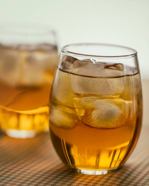 Two glasses of the French aperitif Pineau des Charentes, also called Pineau Charentais or Pineau. It is a fortified wine (mistelle) since Cognac eau-de-vie has been added to it. Trees are reflected in the bottom portion of the glasses.