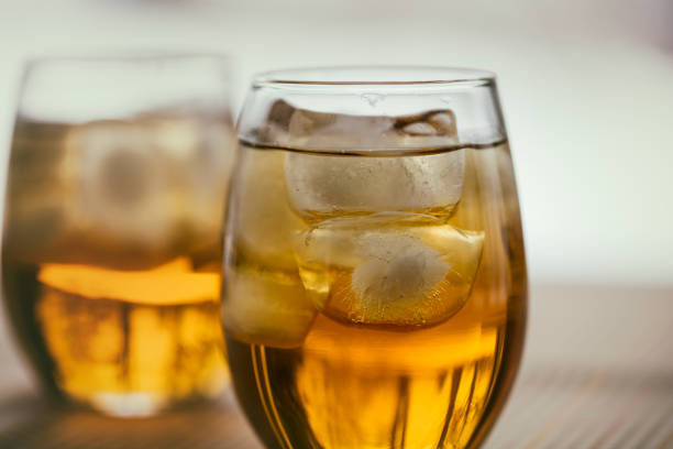 Two glasses of the French aperitif Pineau des Charentes, also called Pineau Charentais or Pineau. It is a fortified wine (mistelle) since Cognac eau-de-vie has been added to it. Trees are reflected in the bottom portion of the glasses.