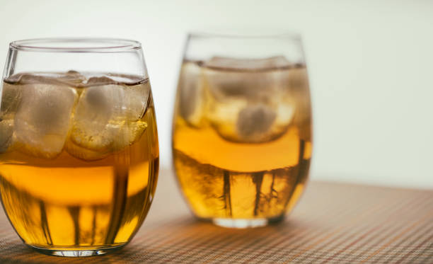 Two glasses of the French aperitif Pineau des Charentes, also called Pineau Charentais or Pineau. It is a fortified wine (mistelle) since Cognac eau-de-vie has been added to it. Trees are reflected in the bottom portion of the glasses.