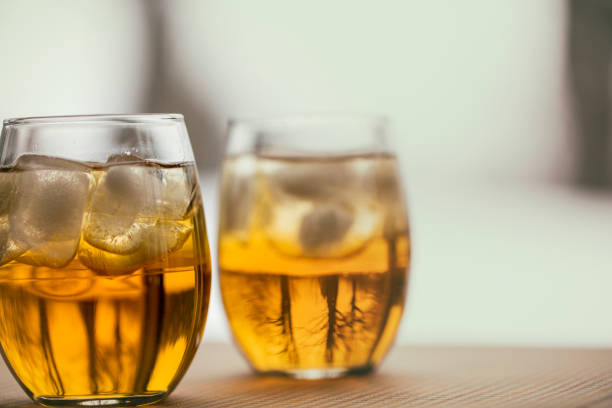 Two glasses of the French aperitif Pineau des Charentes, also called Pineau Charentais or Pineau. It is a fortified wine (mistelle) since Cognac eau-de-vie has been added to it. Trees are reflected in the bottom portion of the glasses.