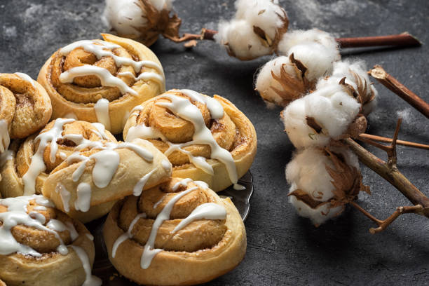 istock fresh cinnamon rolls close up side view, dark grey cement background, cotton boxes behind 641075826